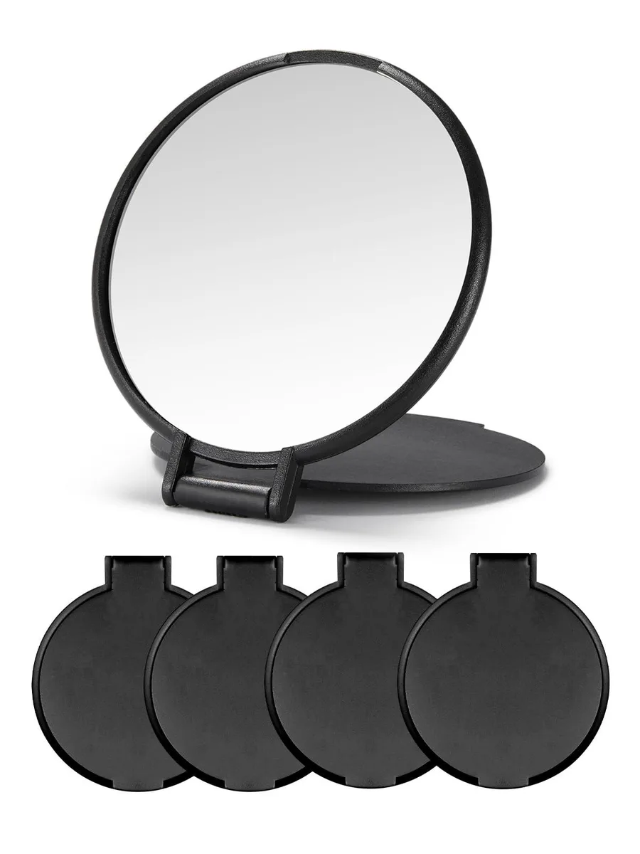 Four small round black plastic mirrors with flip lids lying flat