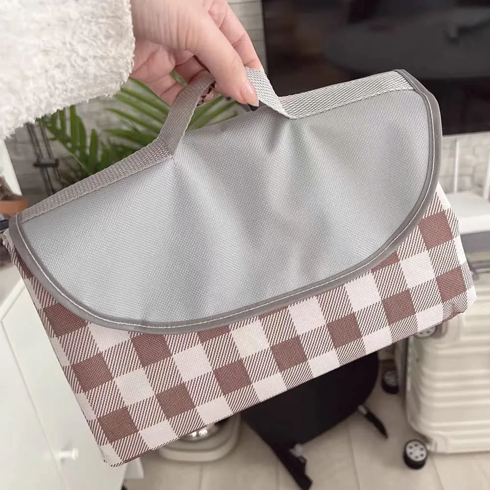 Brown gingham picnic blanket folded into compact rectangle with carry handle