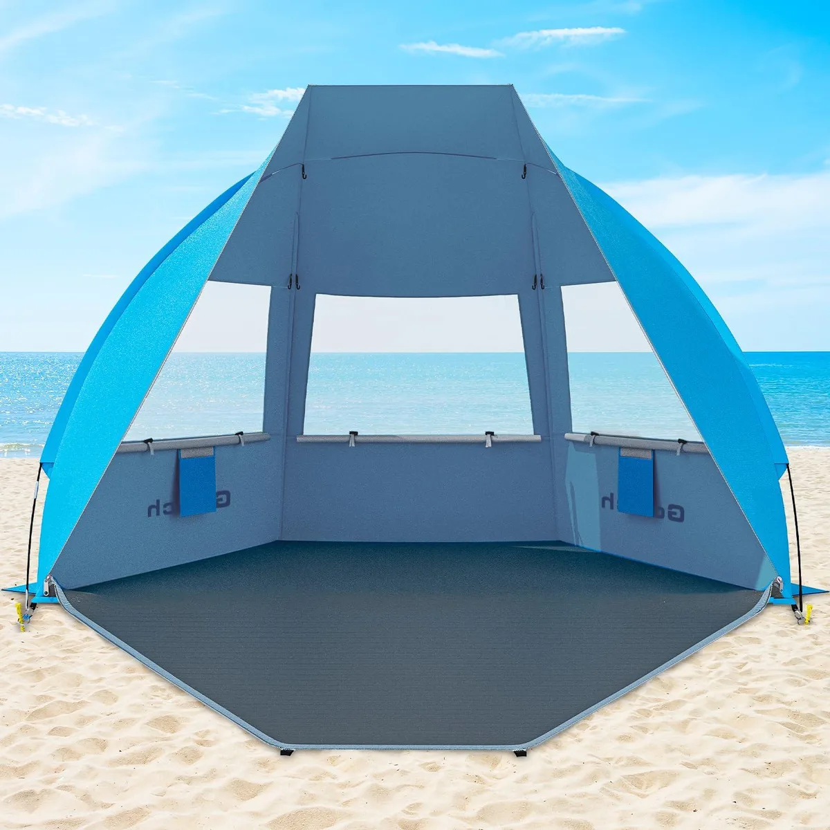 Blue fabric beach tent with fiberglass poles and sand bags, folded carry bag visible
