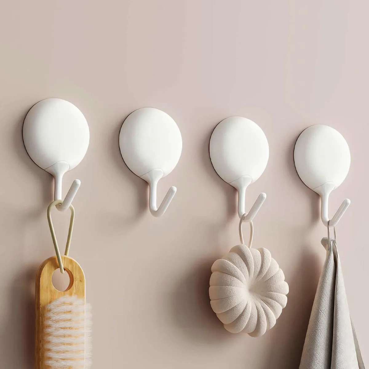 Four white pebble-shaped adhesive hooks on a wall