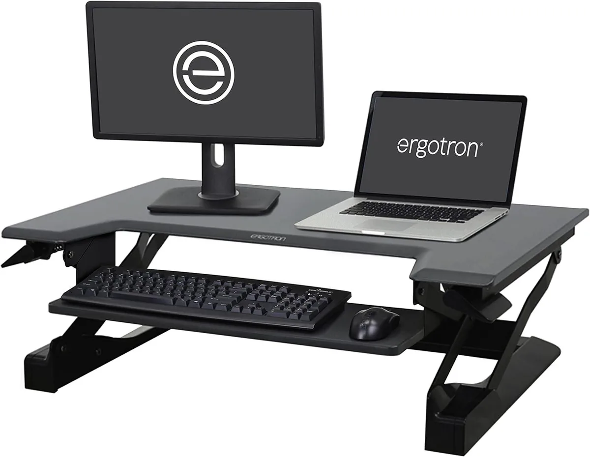 Black standing desk converter with 35-inch worksurface and keyboard tray, sits on tabletop