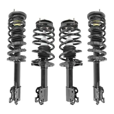Four silver metal strut assemblies with coiled springs and top mounts on a dark surface