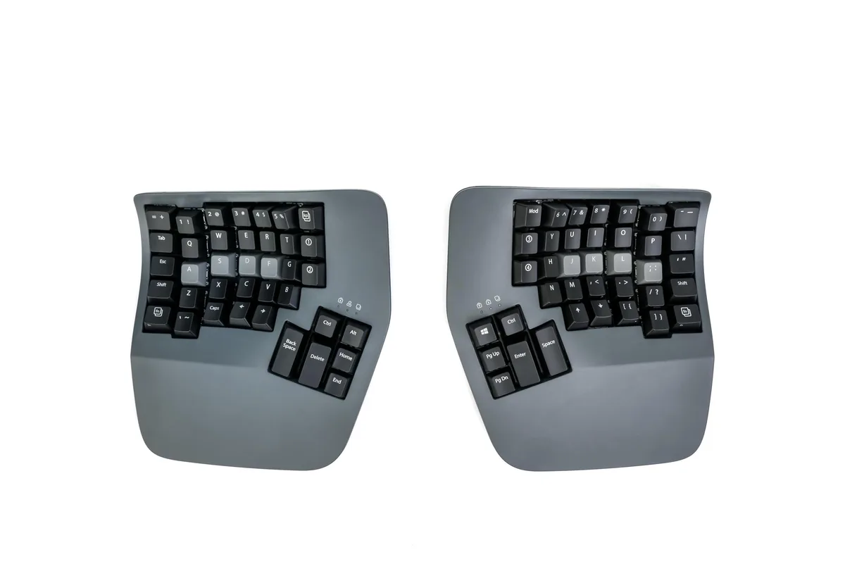 Split ergonomic keyboard with concave key wells, white backlighting, and adjustable tenting legs