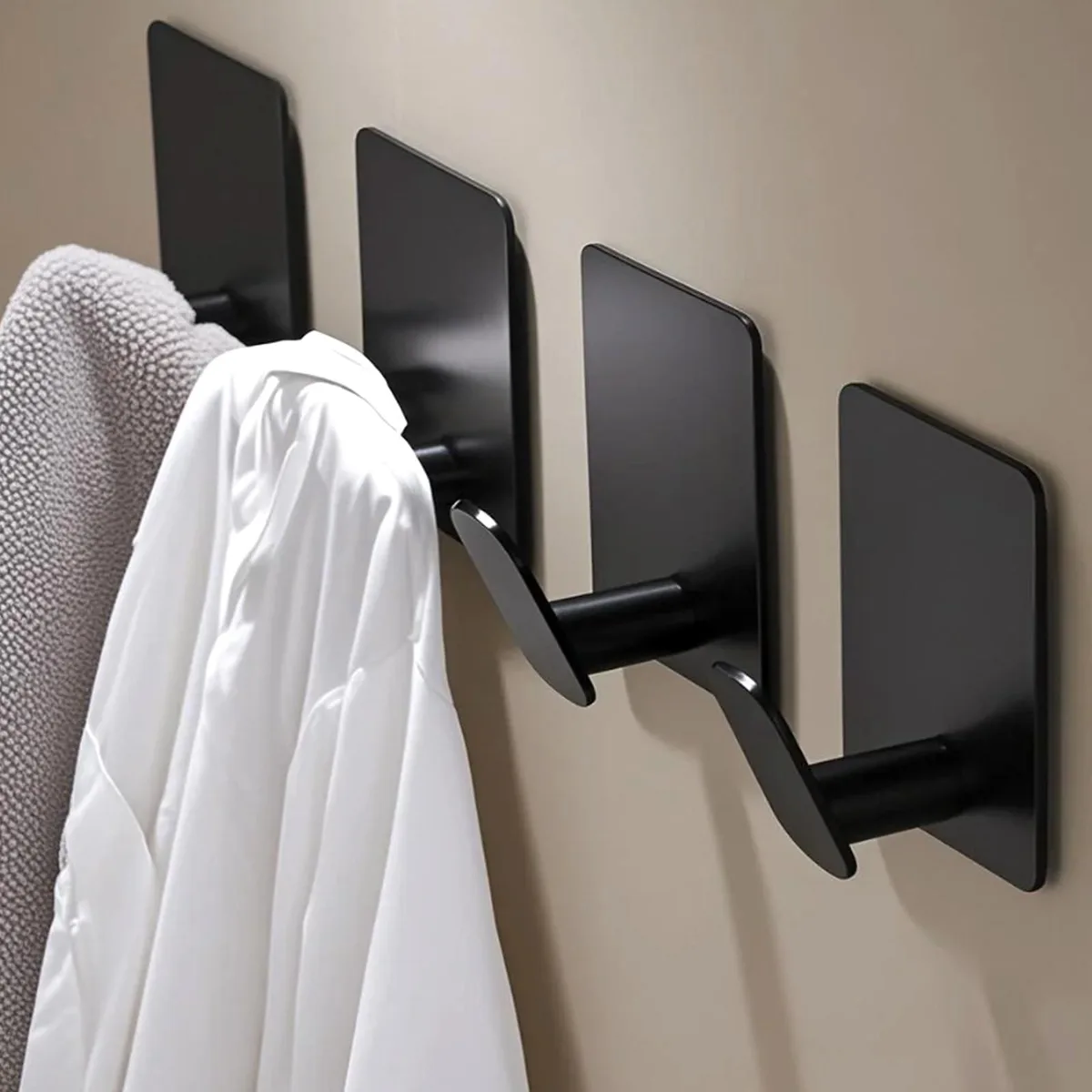 Four matte black stainless steel adhesive hooks on a white background