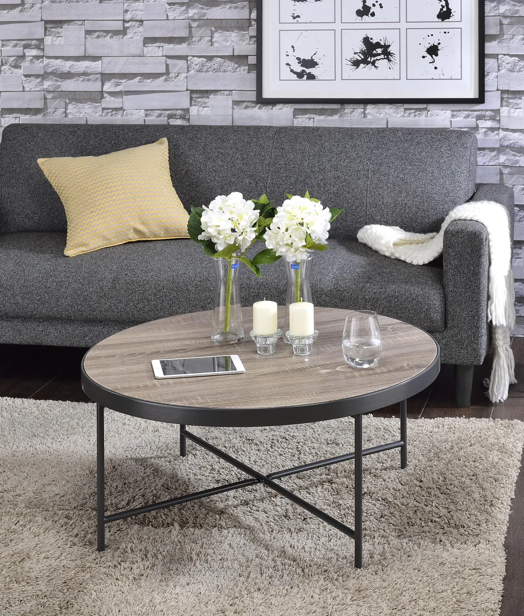 Round coffee table with weathered grey oak top, metal trim, and dark metal X-frame base