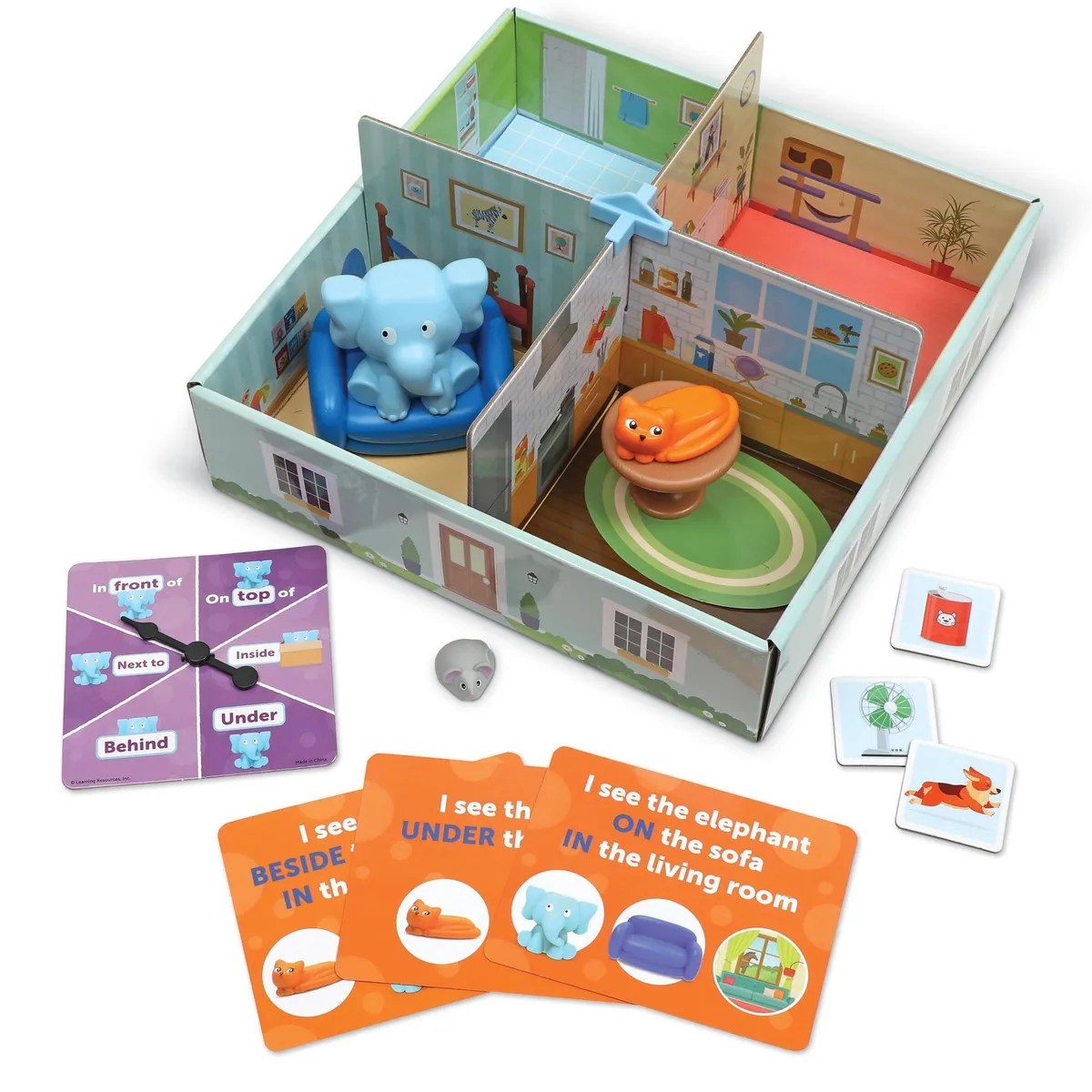 Colorful plastic playset box opening into four furnished rooms with elephant figure, animal pieces, activity cards and spinner