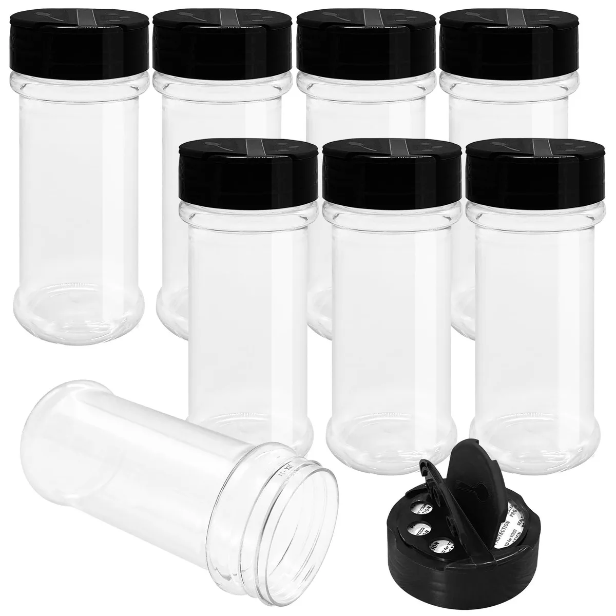 Eight clear round plastic spice jars with black flip-top shaker lids on a white surface
