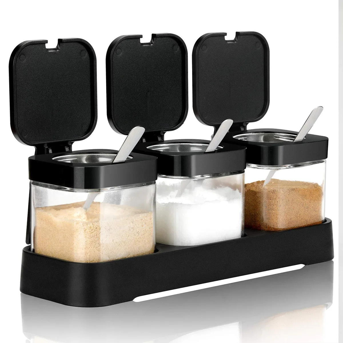 Three clear glass jars with black lids and spoons on a black tray