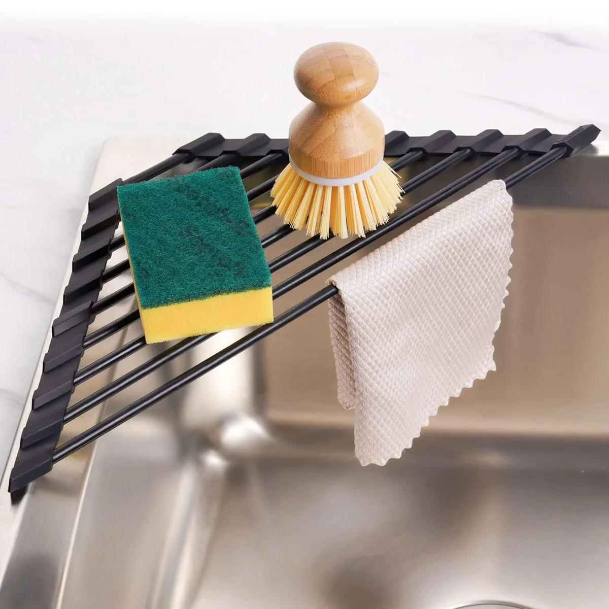 Red triangular roll-up rack with stainless steel rods and silicone coating lying flat over a sink corner