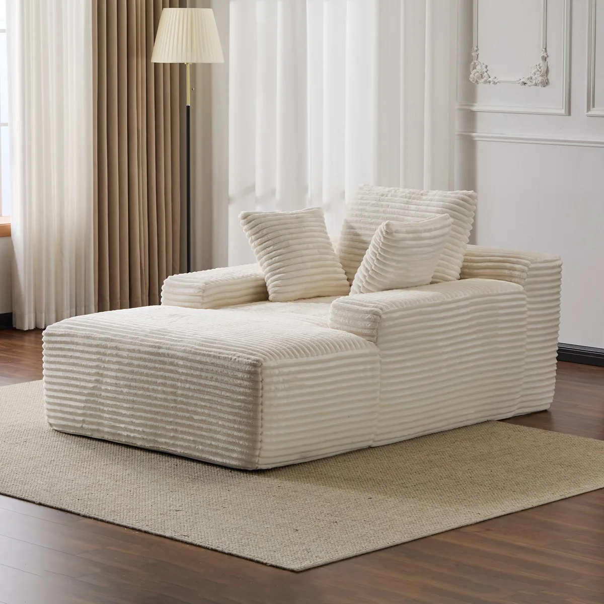 White oversized corduroy chaise lounge with three throw pillows and wide armrests