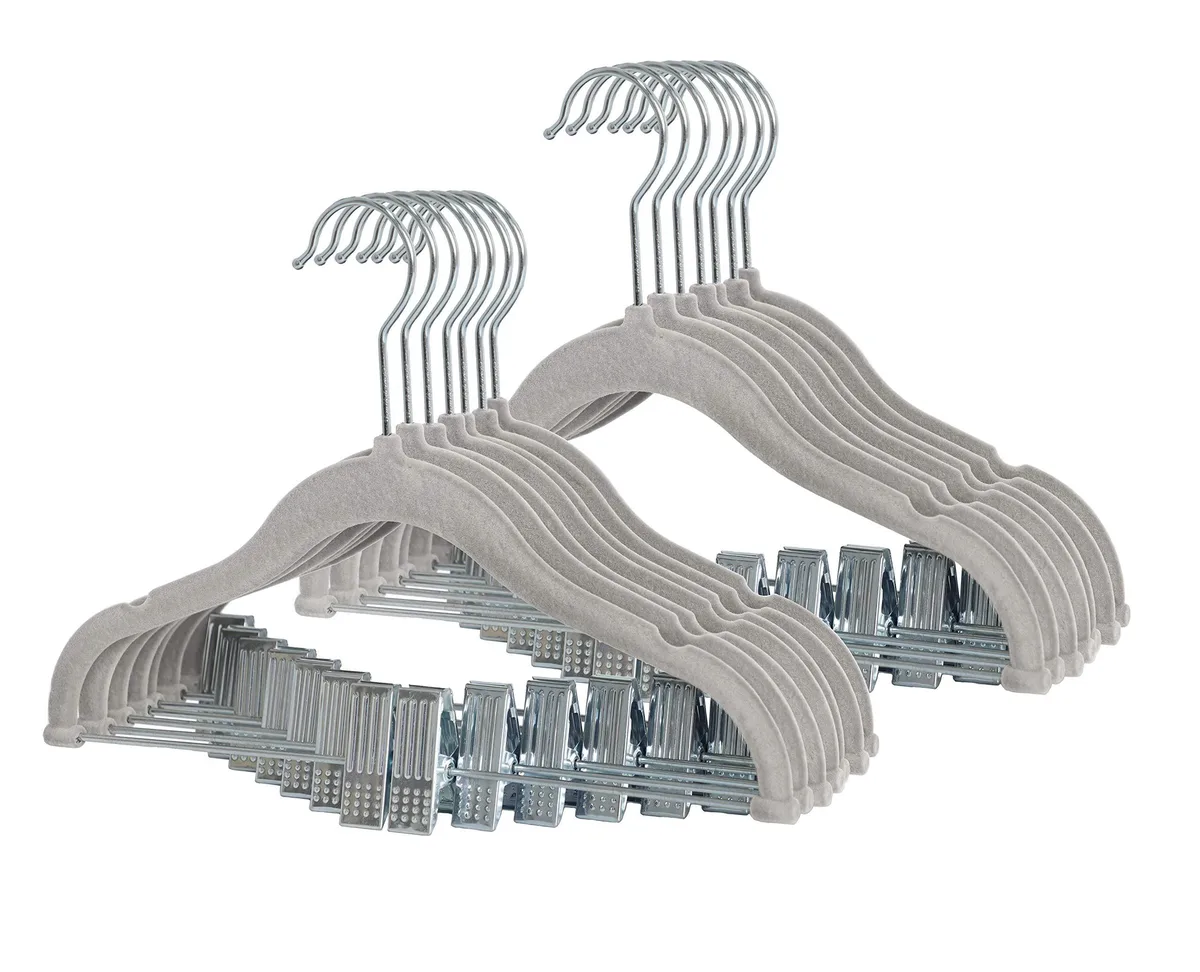 Twenty grey velvet hangers with adjustable clips on a chrome hook