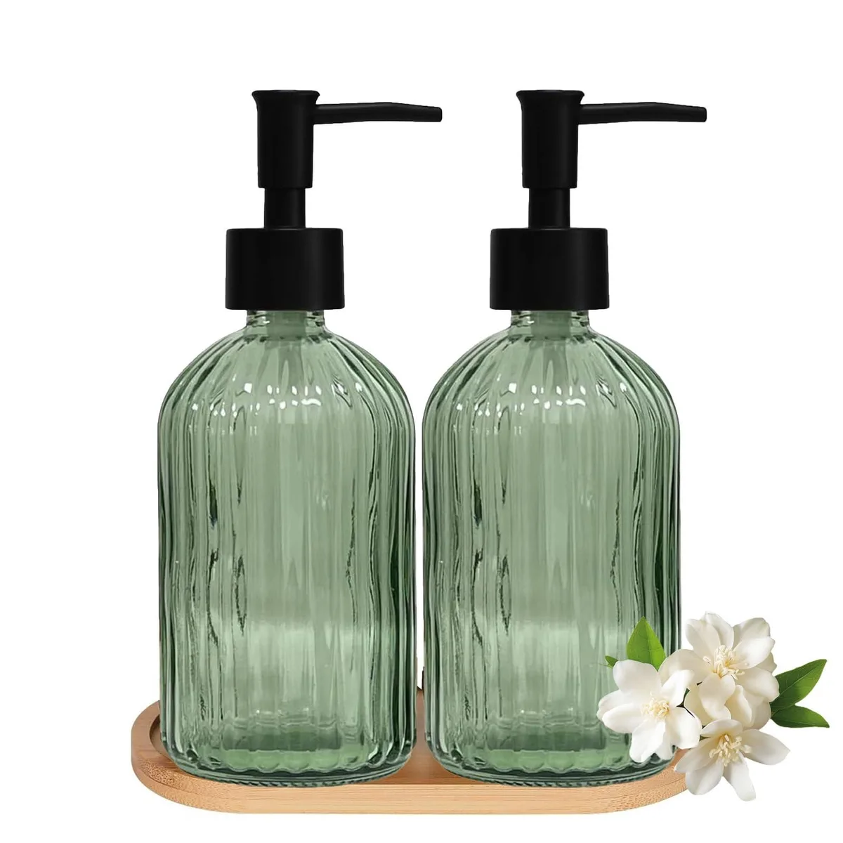 Two green glass soap dispensers with plastic pumps on a bamboo tray