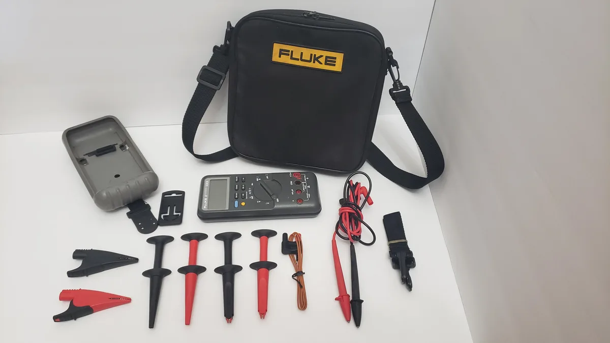 Yellow Fluke 87 digital multimeter with grey rubber holster and black carrying case
