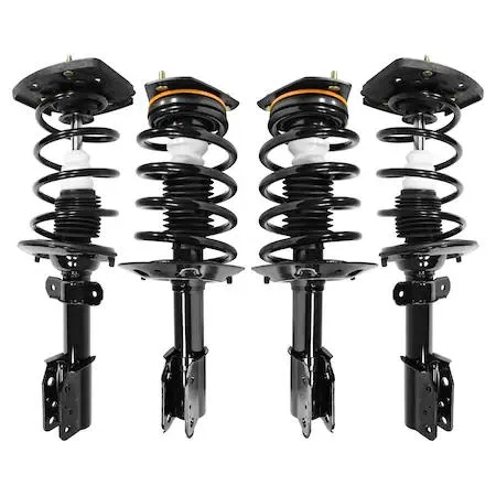 Four silver strut assemblies with coiled springs and top mounts laid out on a surface