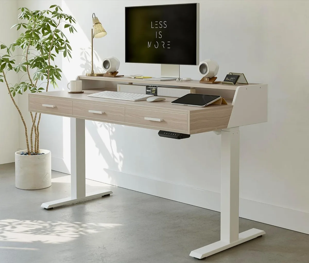Light walnut electric standing desk with three drawers and monitor shelf
