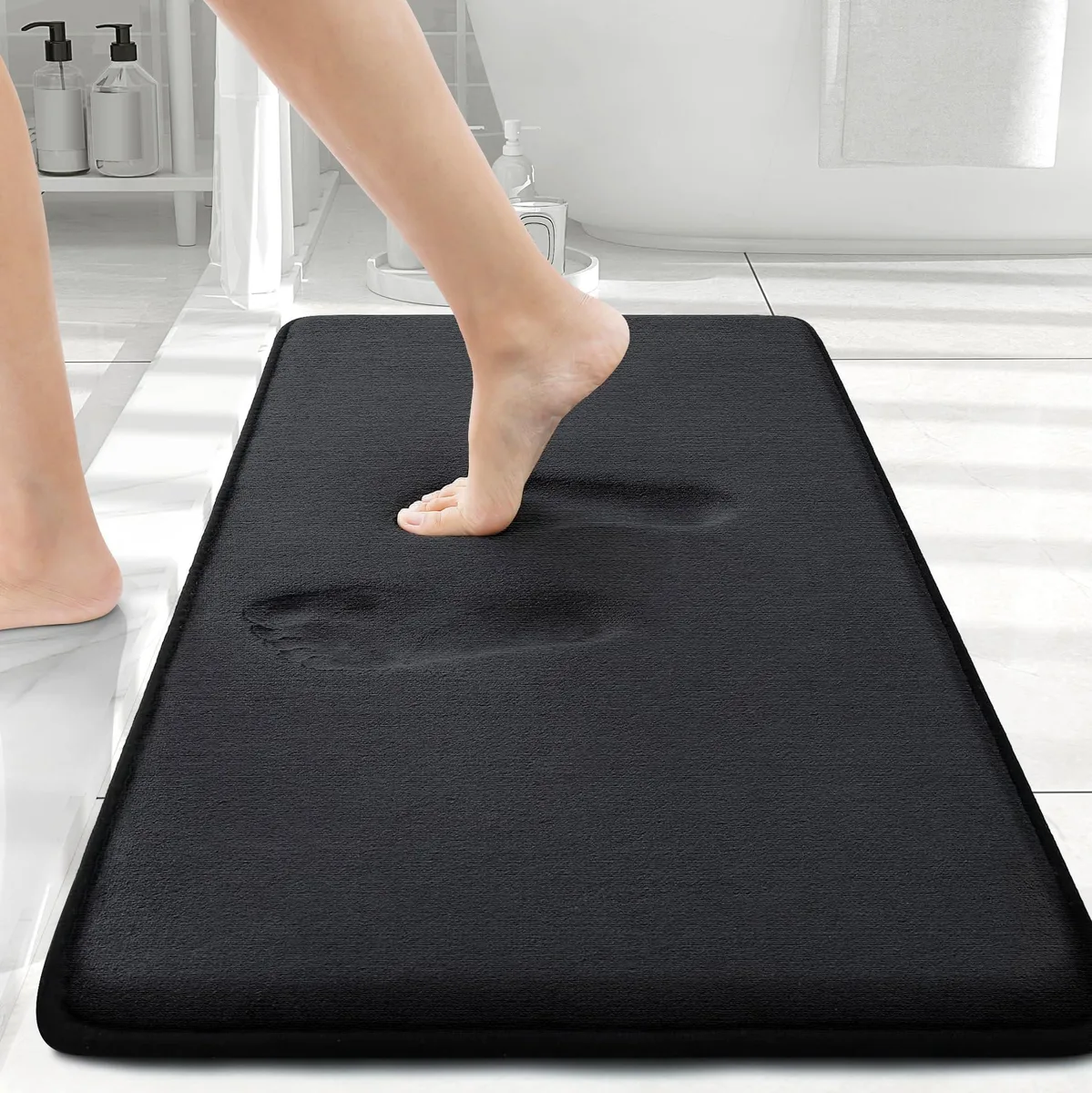 Rectangular black bath mat with plush velvety surface and dotted non-slip backing