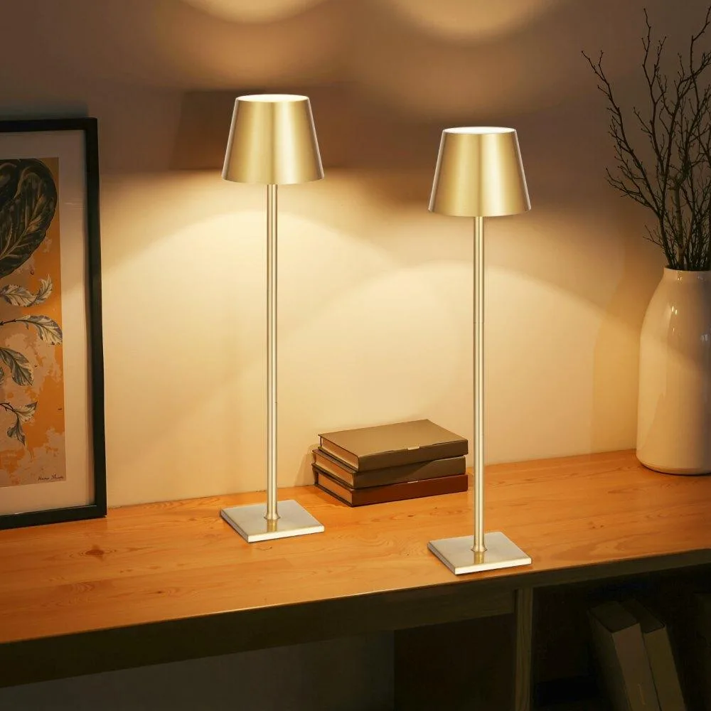 Two gold cordless table lamps with detachable shades, adjustable poles and round bases