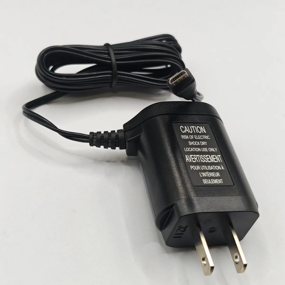 Black rectangular wall charger with folding prongs and a thin output cable