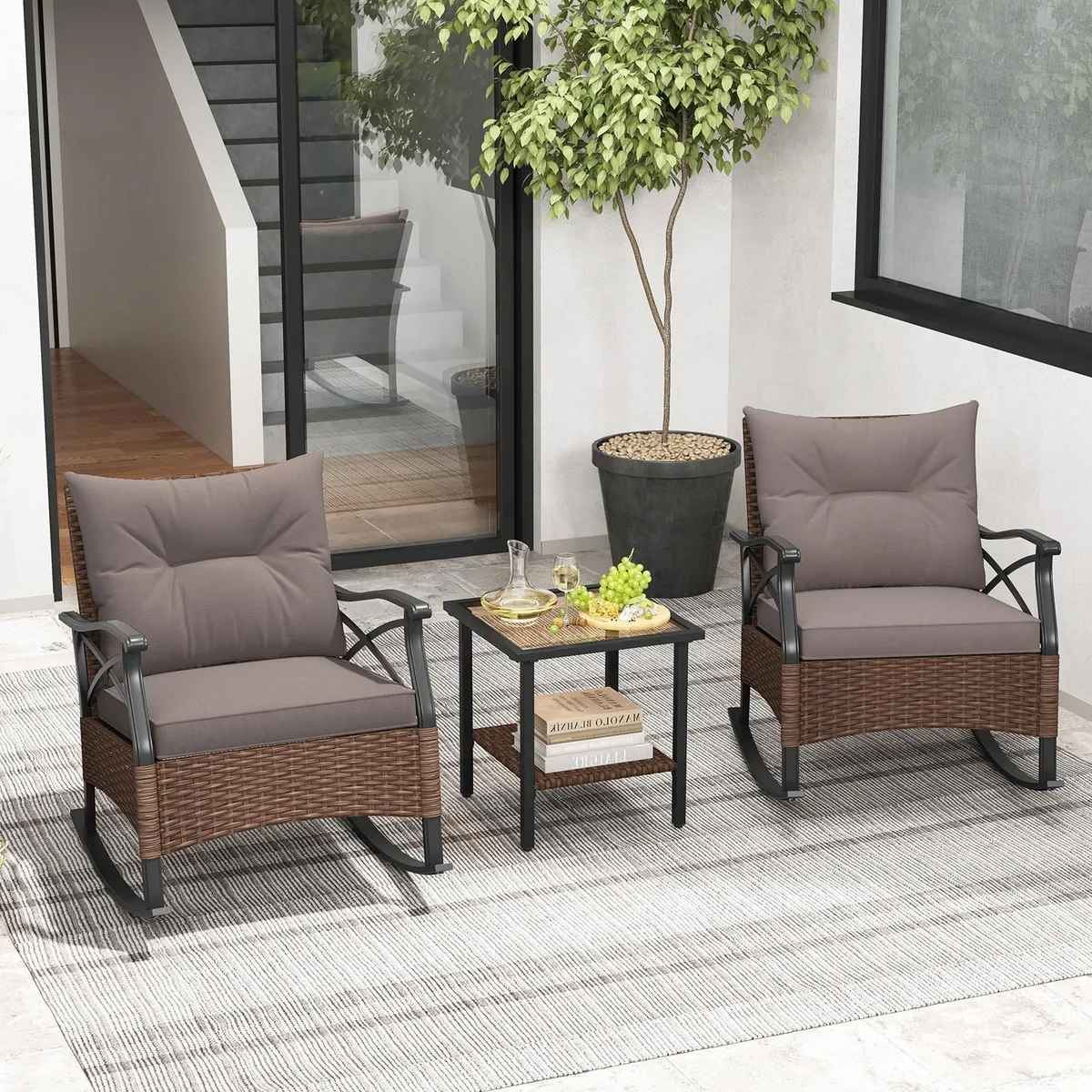 Three-piece brown rattan rocking chair set with grey cushions and two-tier glass-top side table