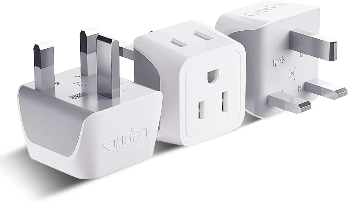 Three compact white Type G travel adapters with dual US sockets