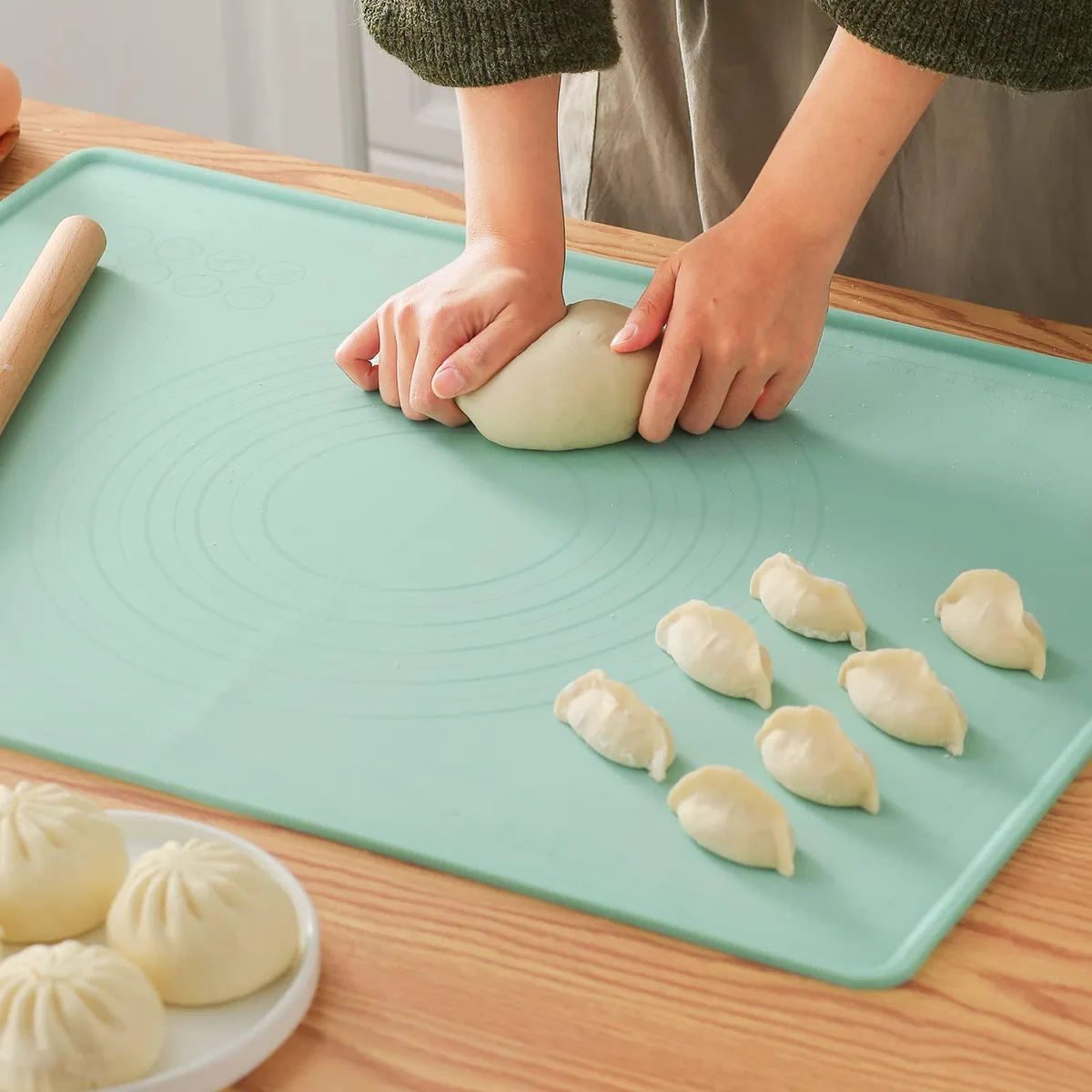 Green rectangular silicone baking mat with raised edges and hanging hole