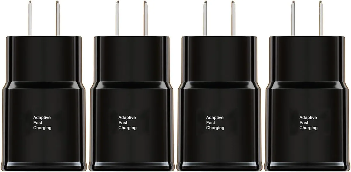 Four white rectangular wall chargers with fold-out plugs on a plain surface