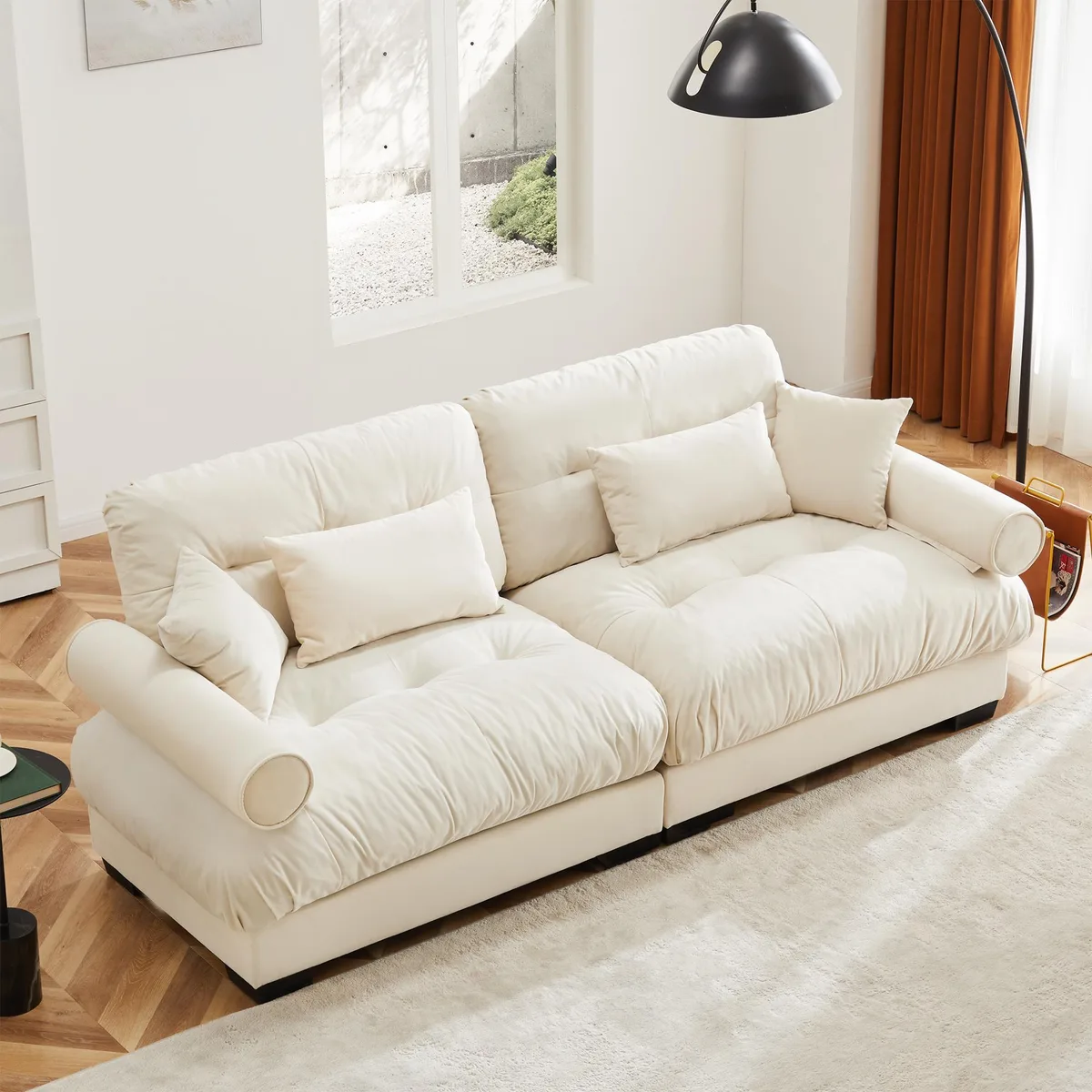 Cream velvet two-seater sofa with bolstered armrests and scatter cushions
