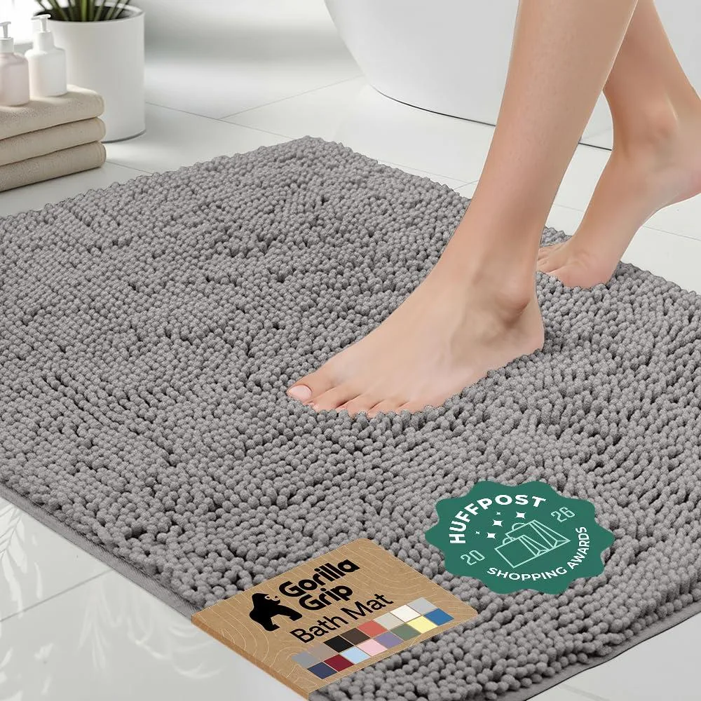 Grey rectangular bath mat with fluffy chenille surface and rubber backing, 24 by 17 inches