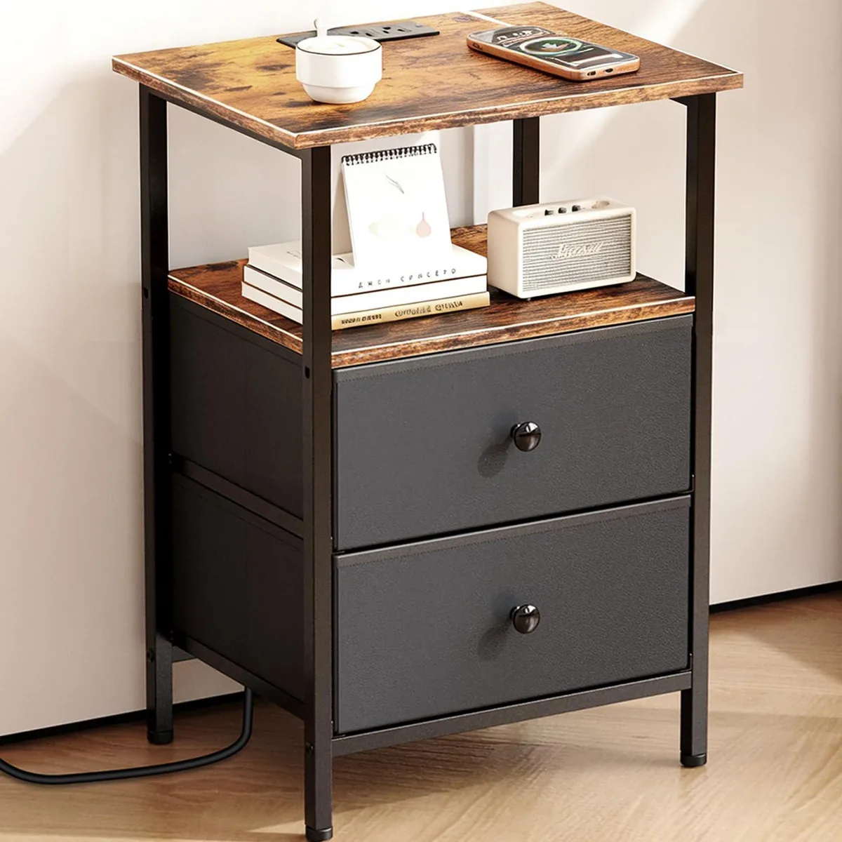 Compact brown-black nightstand with metal frame, two fabric drawers, open shelf and built-in charging ports