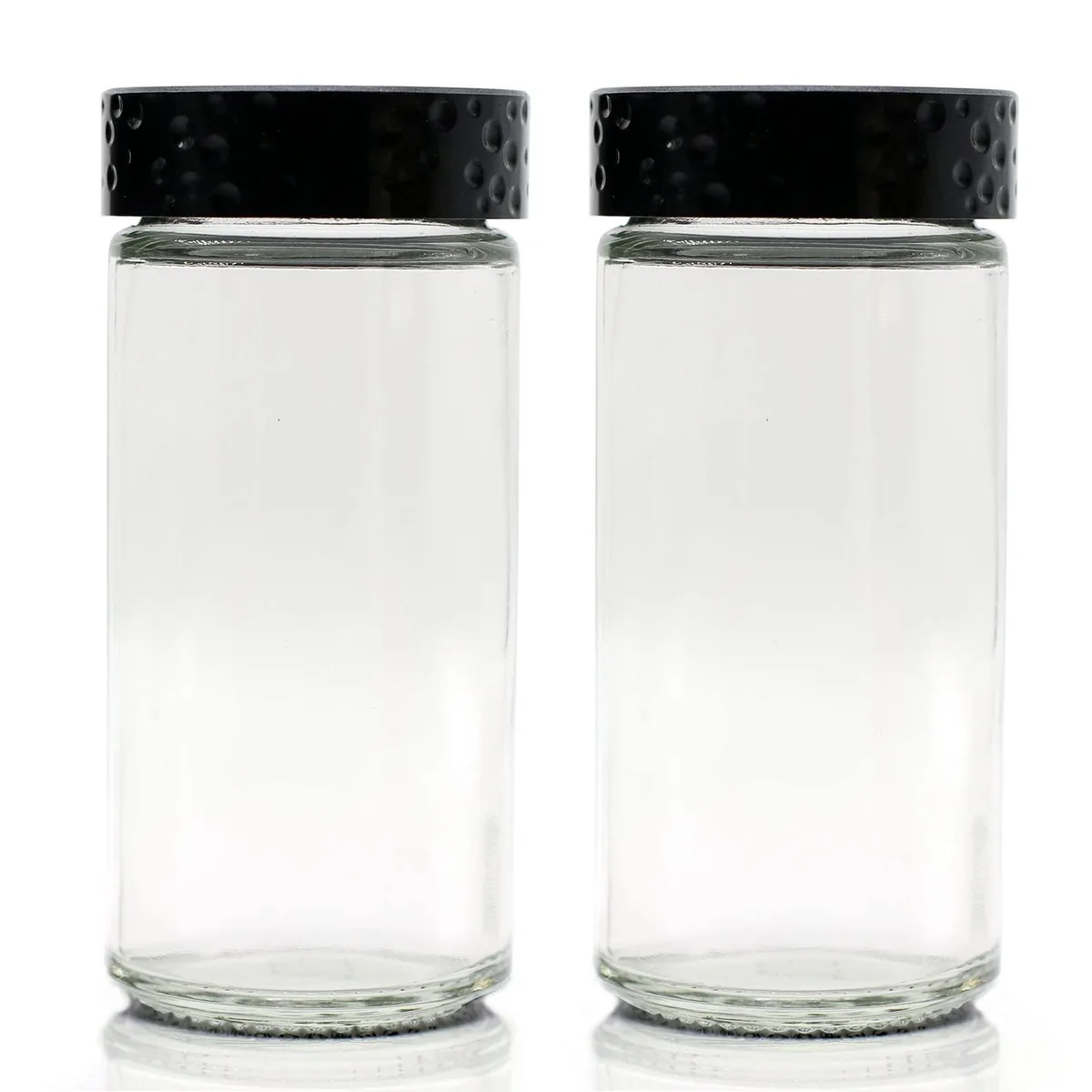 Two clear round glass spice jars with black plastic caps and shaker lids