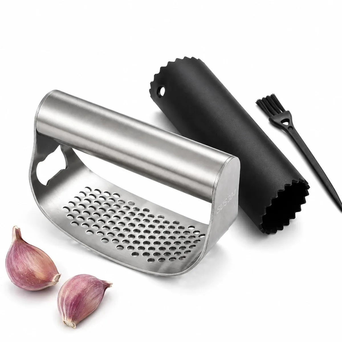 Stainless steel garlic rocker, black silicone peeler tube, and mini cleaning brush on a flat surface