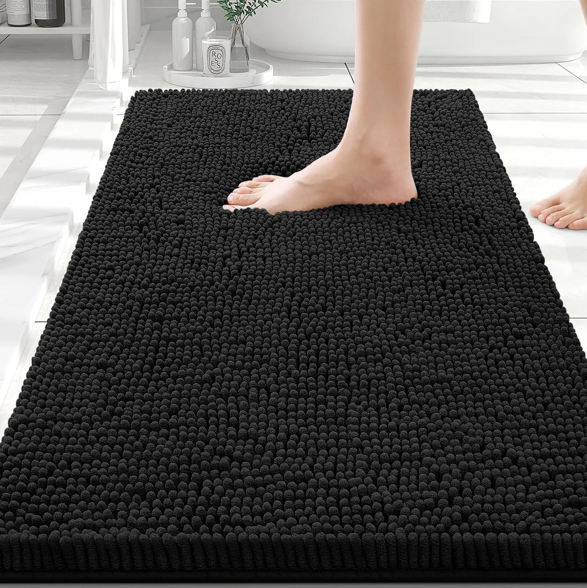 Black rectangular chenille bath mat with plush shaggy surface and non-slip PVC backing