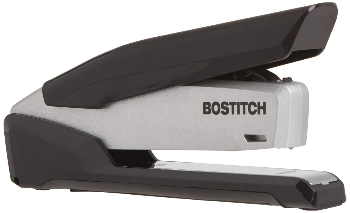 Black and gray metal desktop stapler with rubber grip, spring-powered mechanism, built-in staple remover and storage compartment