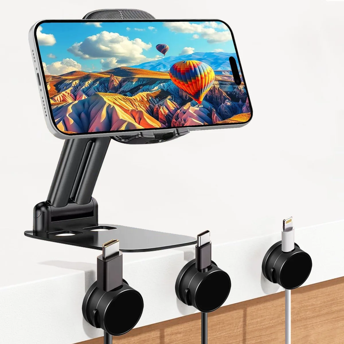 Black foldable phone stand with weighted metal base and three magnetic cable clips on a desktop