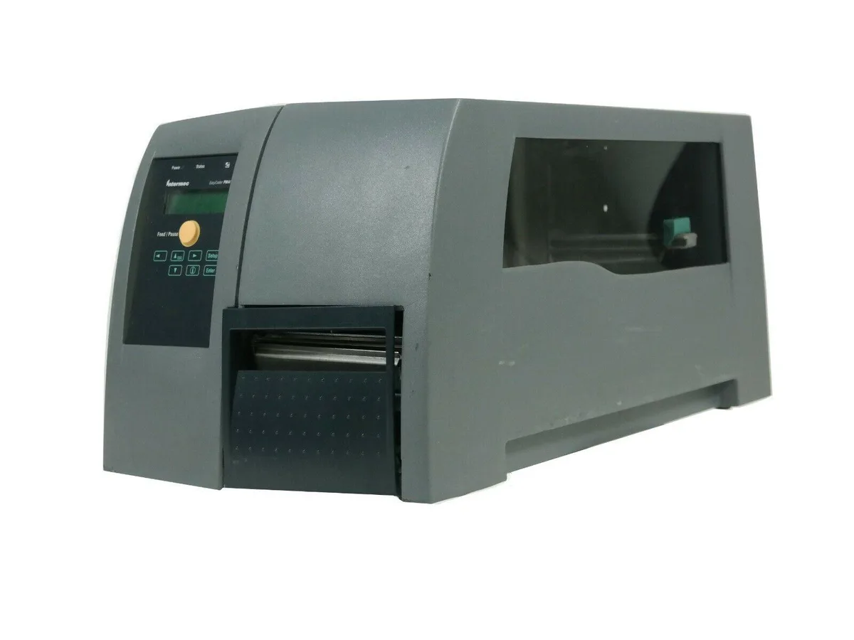 Intermec PM4i thermal label printer, matte grey industrial housing, front media window, control panel with display, power cord attached