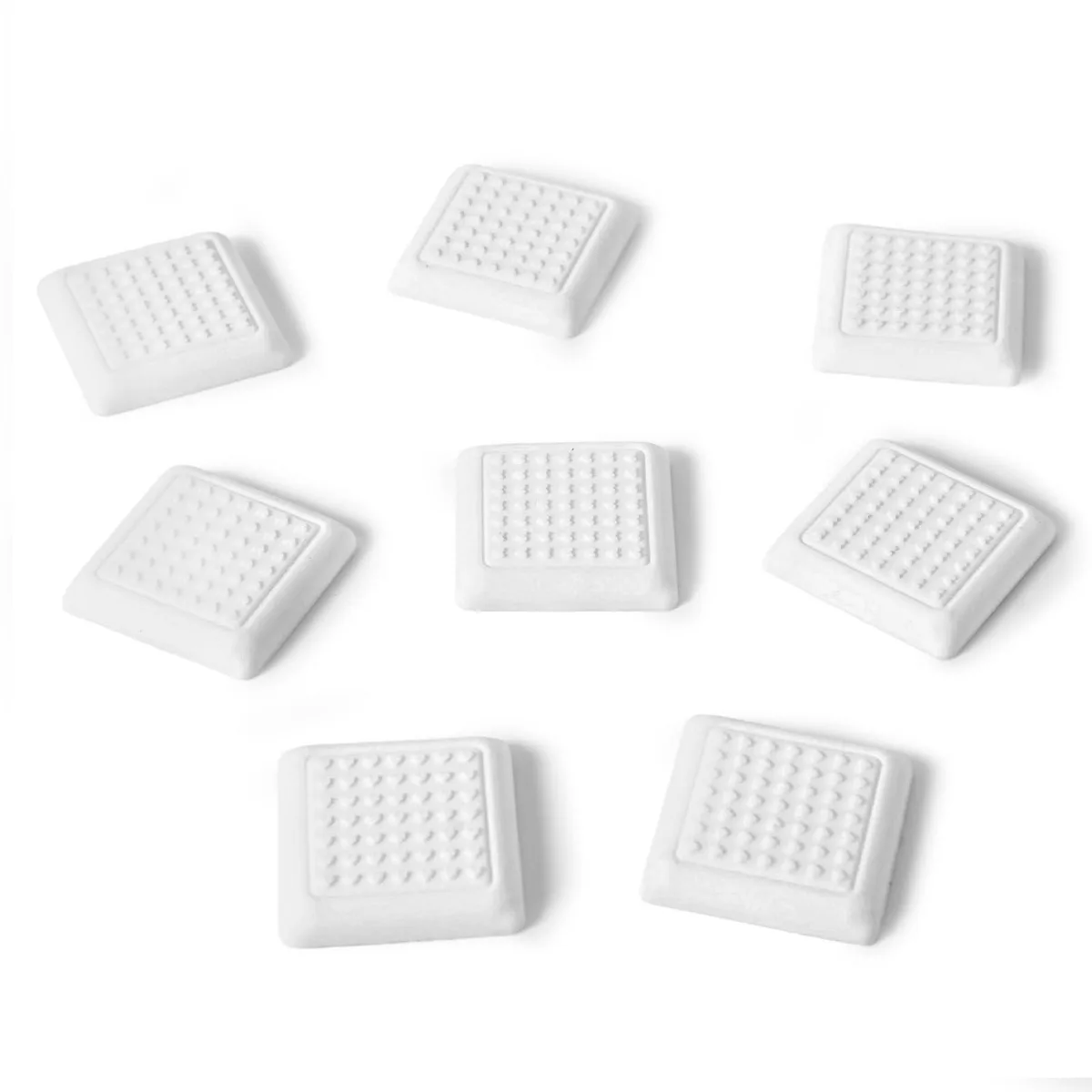 Eight white square silicone feet with adhesive backing on a plain surface