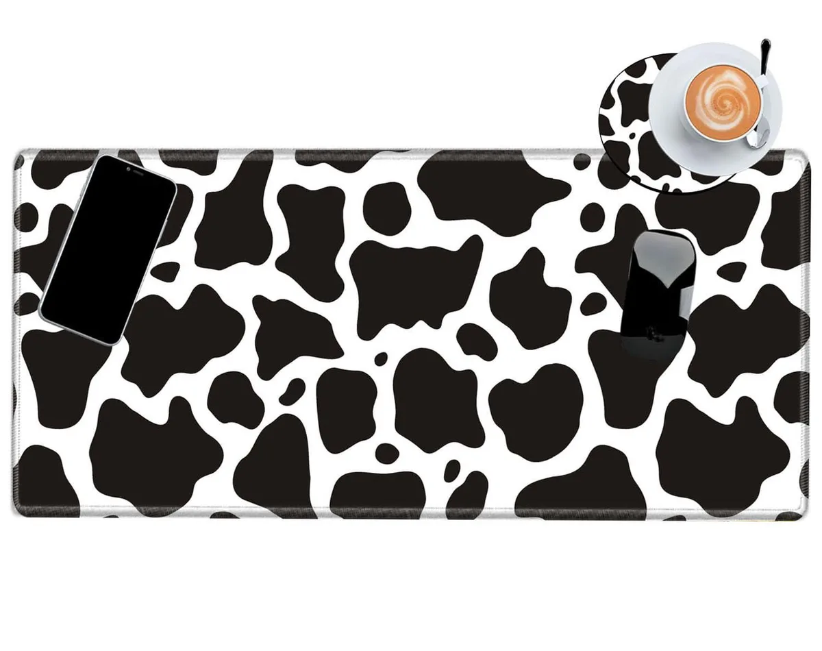 Rectangular black-and-white cow-print desk mat, 24 by 12 inches, thin rubber base with stitched edges