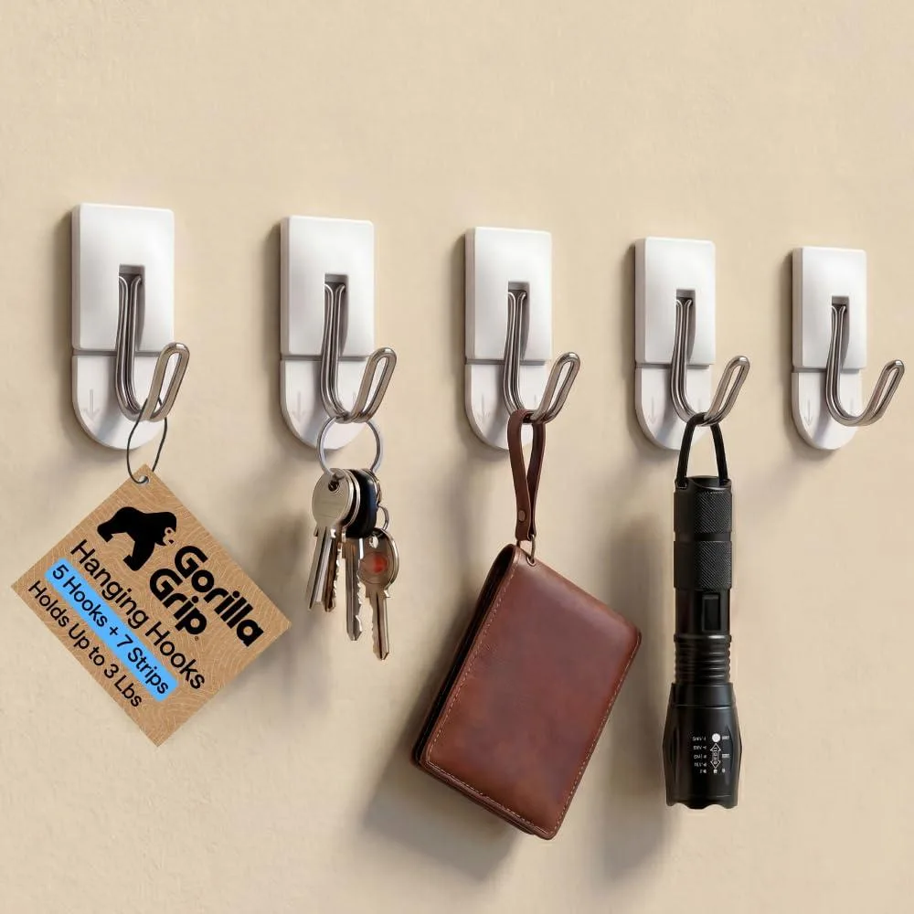 Five small silver metal hooks with adhesive backing strips on a light surface