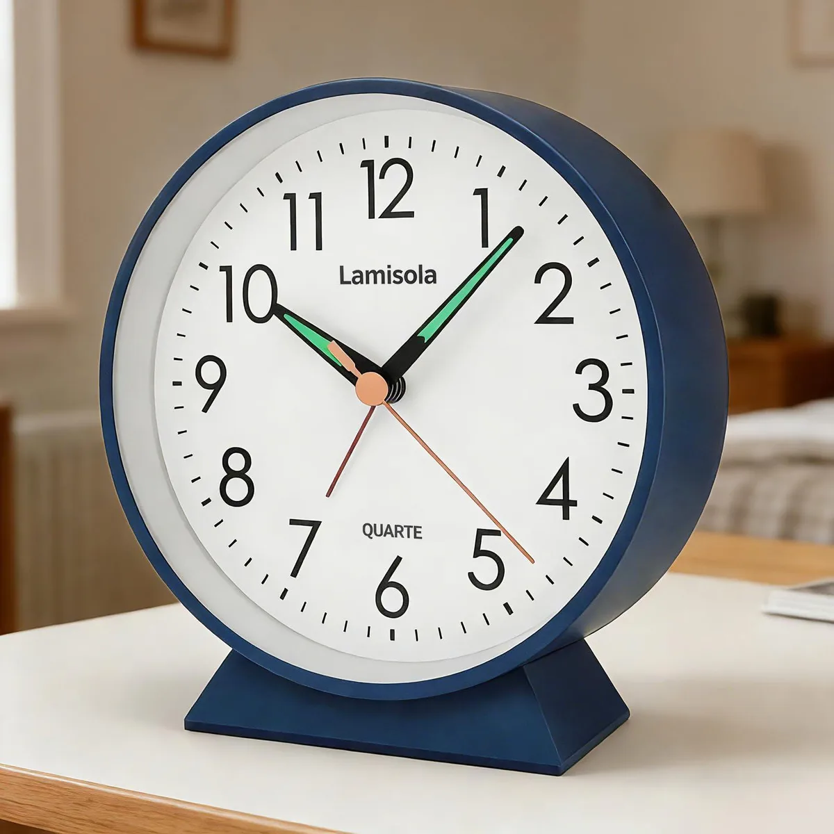 Small navy blue metal analog alarm clock with classic dial