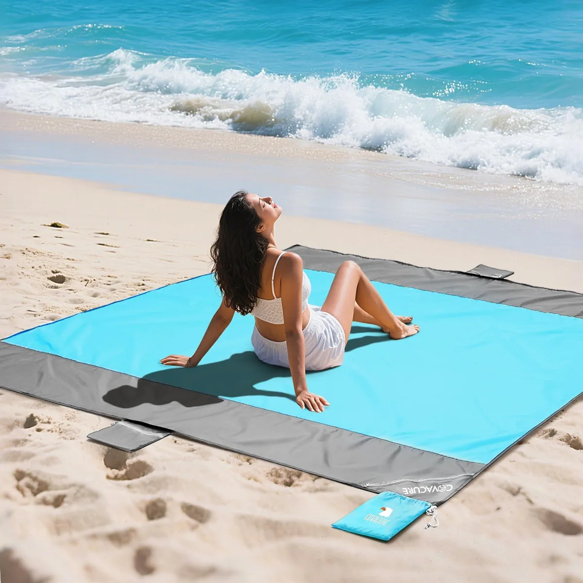 Navy blue rectangular beach blanket folded compact with attached carry pouch and carabiner