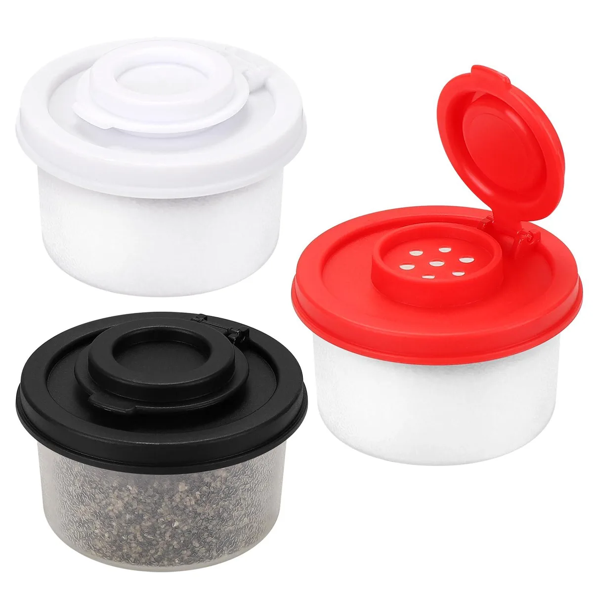 Three small cylindrical spice shakers in black, white and red standing together