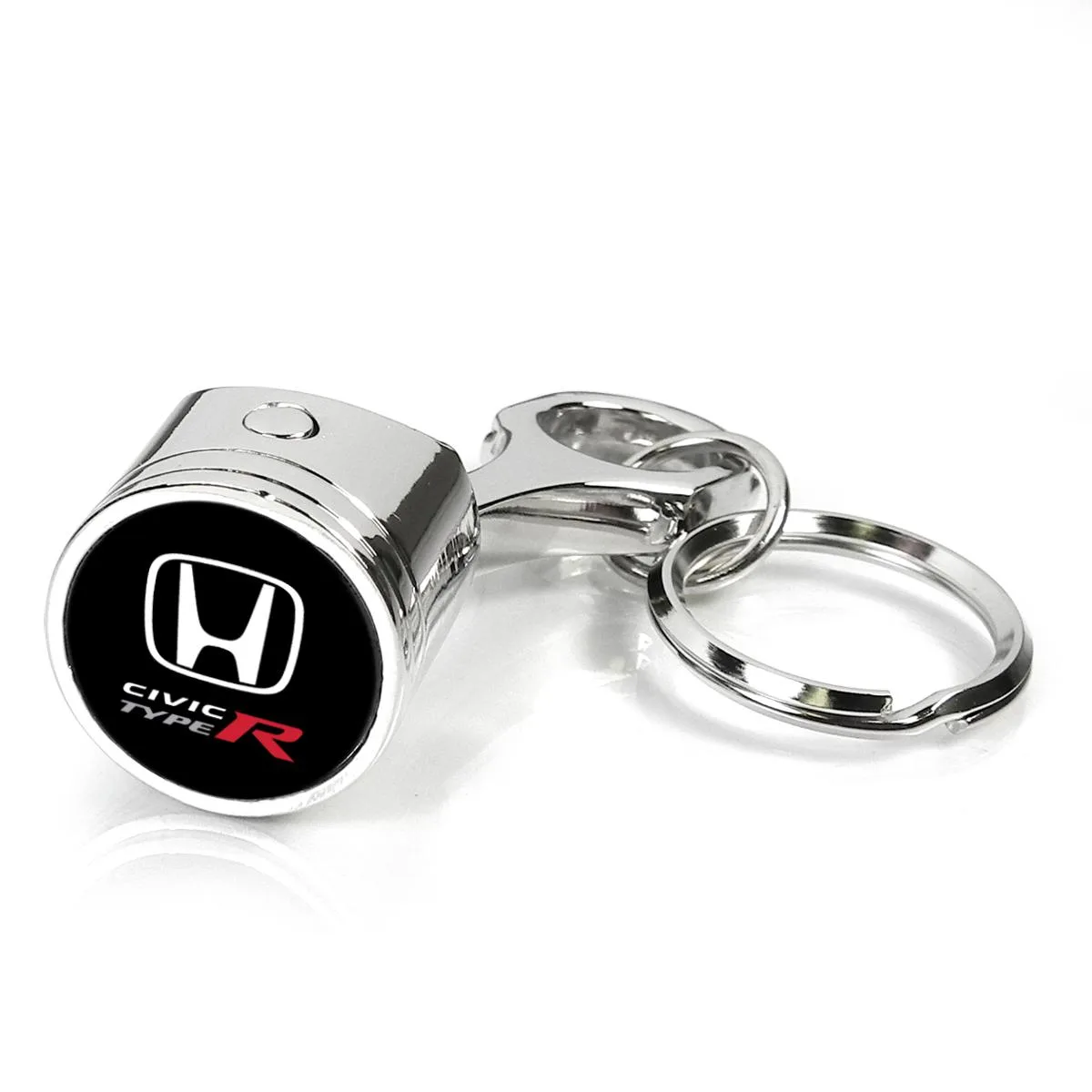 Chrome metal key chain shaped like a piston and connecting rod with a domed logo