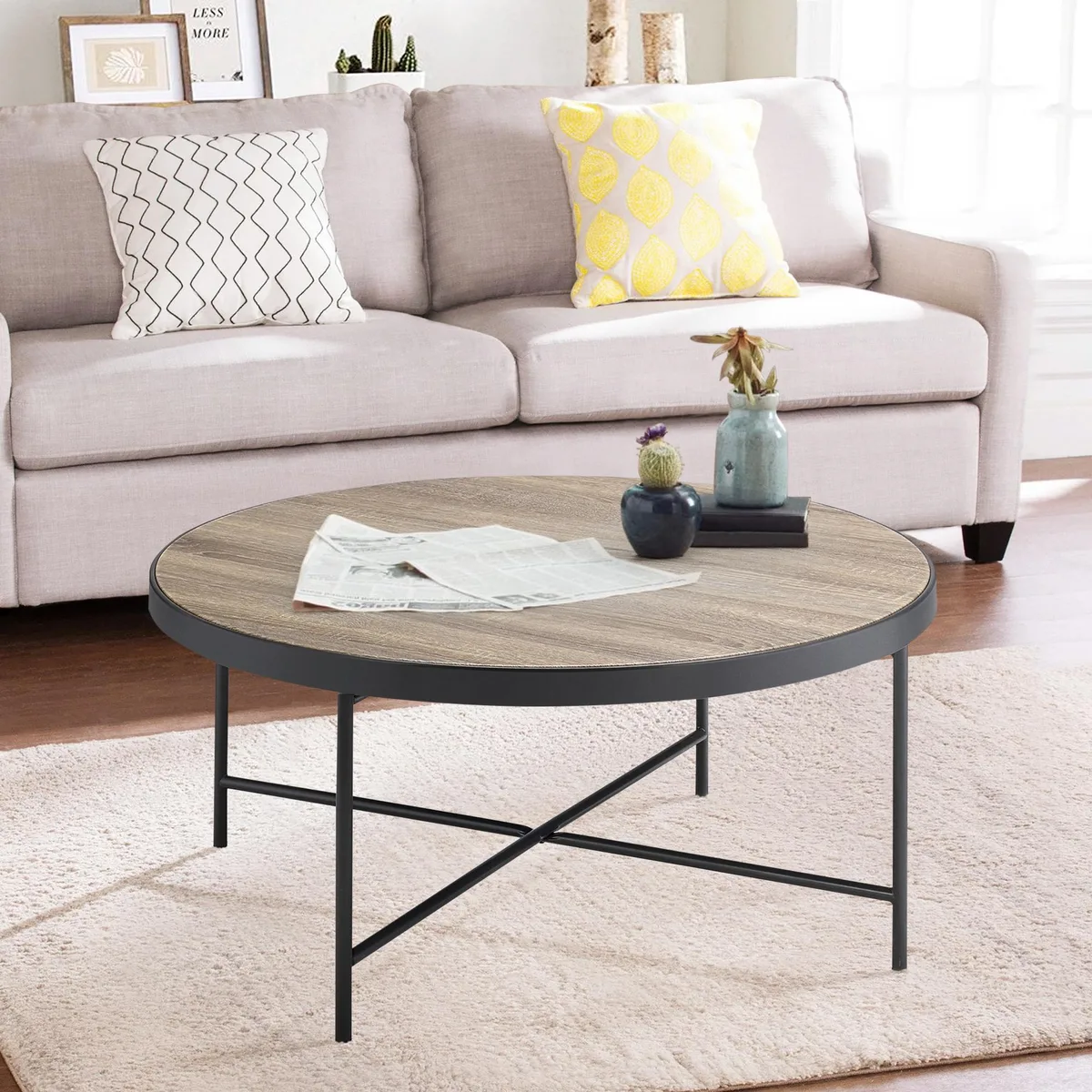 Round weathered grey oak coffee table with black metal trim and X crossbar base