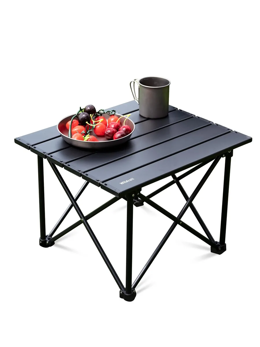 Compact black aluminum folding table with four triangular legs and carry bag