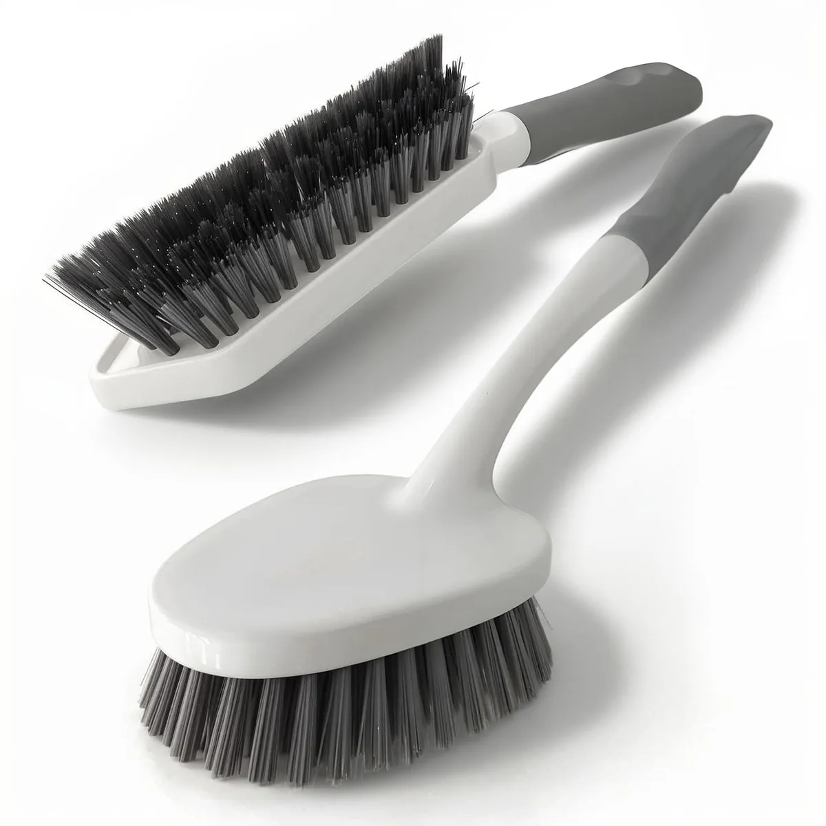 Two white scrub brushes with stiff bristles and long handles with hanging holes