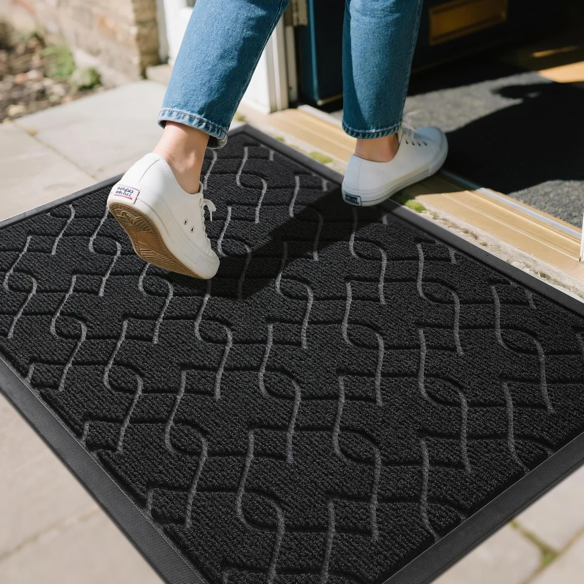 Black rectangular door mat with striped woven surface and thin rubber border, low-profile design