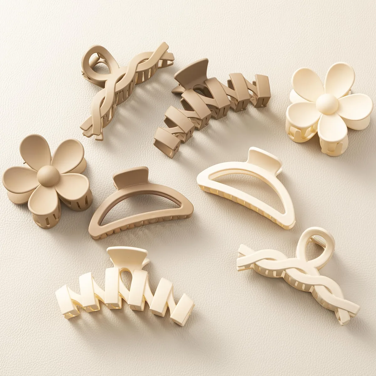 Eight cream and beige flower claw clips on a light background