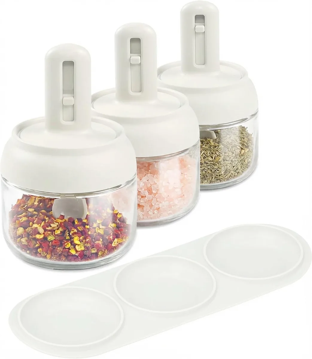 Three clear glass jars with red lids and retractable spoons on a tray