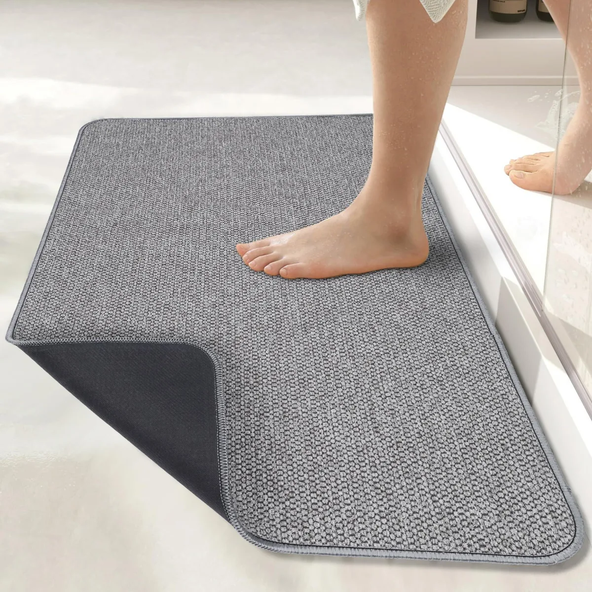 Grey rectangular bath mat, ultra-thin .2 inch profile, fabric surface with rubber backing, 17 by 27 inches