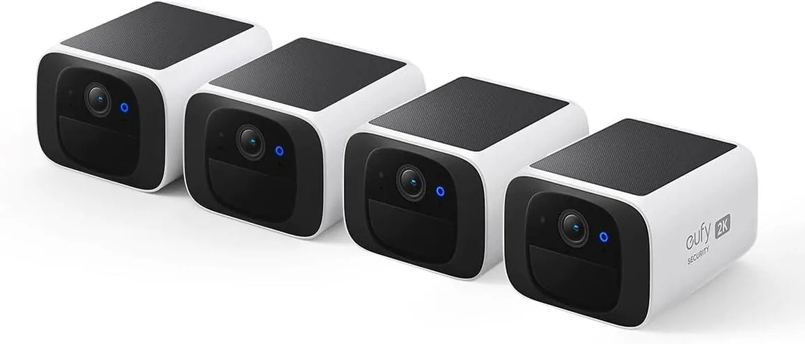 Four compact white rectangular cameras with solar panels on top, wall-mount brackets attached, shown together as a set